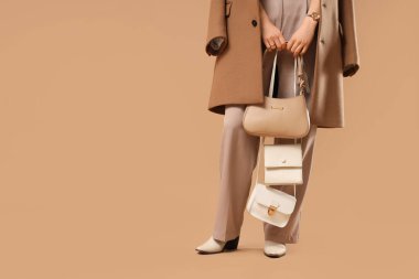 Bej arka planda farklı tarz çantaları olan güzel bir genç kadın, yakın plan.