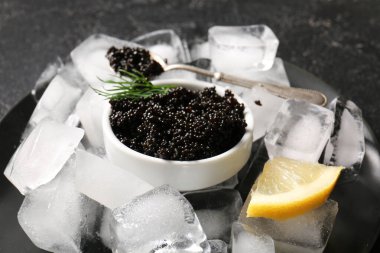 Koyu arkaplanda dereotu olan bir kase dolusu lezzetli siyah havyar.