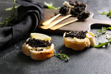 Koyu arkaplanda lezzetli siyah havyarlı kaşık ve baget dilimleri.