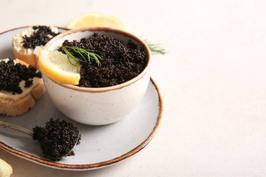 Beyaz arka planda leziz siyah havyar dilimleri ile kâse ve baget dilimleri.