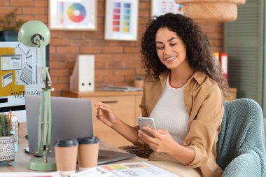 Ofiste cep telefonuyla çalışan Afro-Amerikalı bir web tasarımcısı.