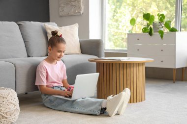 Evde dizüstü bilgisayar kullanan küçük kız.