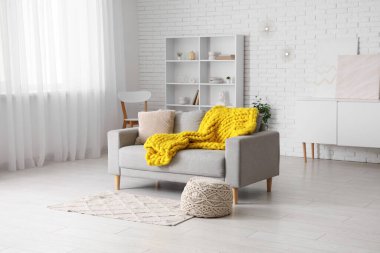 Modern oturma odası, şık gri kanepe, puf ve sarı ekose örgü.