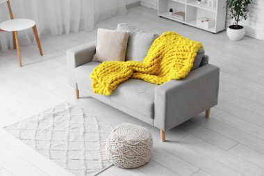 Modern oturma odası, şık gri kanepe, puf ve sarı ekose örgü.