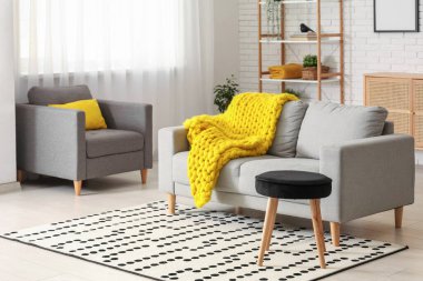 Modern oturma odası, şık gri kanepe, koltuk ve sarı örülü ekose.