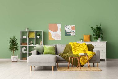 Modern oturma odası, şık bir kanepe, masalar ve sarı örülü ekose kumaş.