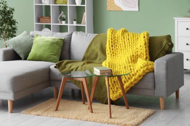 Modern oturma odası, şık bir kanepe, masalar ve sarı örülü ekose kumaş.