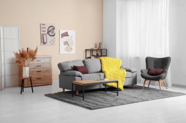 Şık kanepesi, koltuğu ve sarı örülü ekoseli modern oturma odası.