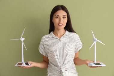 Arka planda rüzgar türbini modelleri olan genç bir Asyalı kadın. Yeşil enerji kavramı