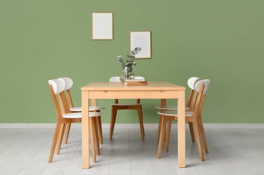 Vazoda okaliptüs dalları ve yemek odasının içindeki kitaplarla dolu bir masa.