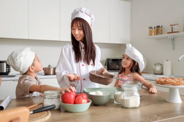 Yemekleri ve küçük çocukları mutfakta olan Asyalı bir kadın şef.