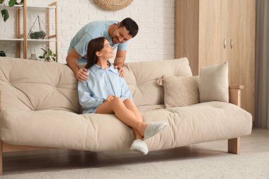 Evdeki kanepede pijamalı mutlu bir çift.