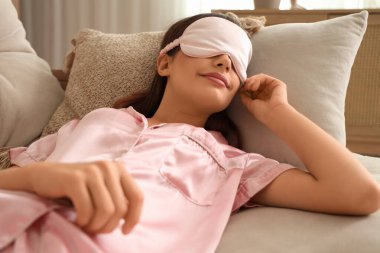 Evdeki kanepede pijamalı, genç ve güzel bir kadın uyuyor.