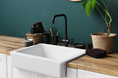 Banyoda yeşil duvarın yanında banyo aksesuarları ve bitkiler var.