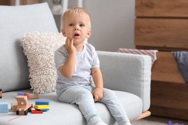 Evdeki kanepede oyuncaklarla ağlayan bebek.