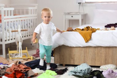 Küplü yaramaz oğlan dağınık yatak odasında yürüyor.