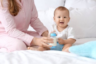 Annem yatak odasında ona küçük bir şişe süt veriyor, yakın plan.