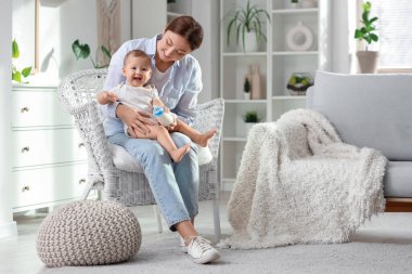 Annem, evdeki koltukta küçük şirin süt şişesini veriyor.