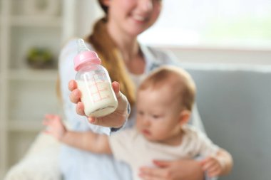 Anne evde süt şişesi ve küçük bebeğiyle, yakın plan.