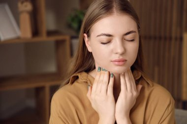 Tiroid bezini evde inceleyen genç bir kadın, yakın plan.