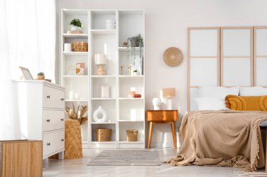 Büyük yataklı, katlanır ekranlı ve pencerenin yanındaki raflı modern yatak odasının içi.