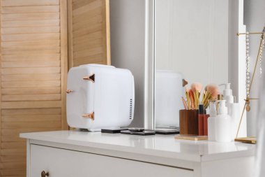 Kozmetik ürünleri, aksesuarlar ve küçük buzdolabı ile giyinme masası.