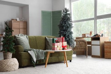 Noel ağaçları ve hediye kutularıyla aydınlık oturma odasının şık bir iç mekanı.