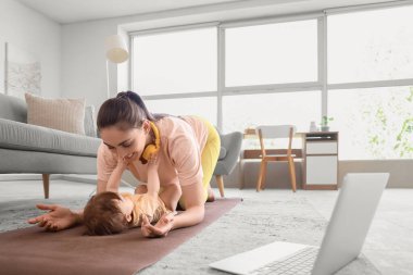 Küçük bebeğiyle evde yoga minderinde yatan sportif bir anne.
