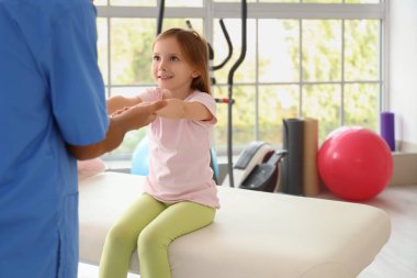 Rehabilitasyon merkezinde küçük bir kızla çalışan fizyoterapist.