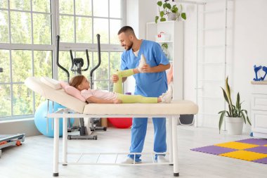 Rehabilitasyon merkezinde küçük bir kızla çalışan erkek fizyoterapist.