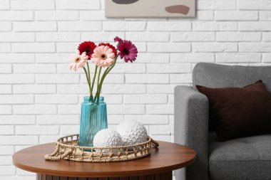 Vazodaki güzel Gerbera çiçekleri ve oturma odasındaki masada hasır tepsi.