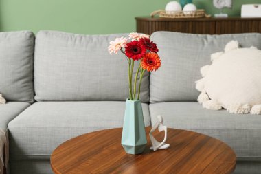 Gerbera çiçekli vazo ve biblo oturma odasındaki masada.