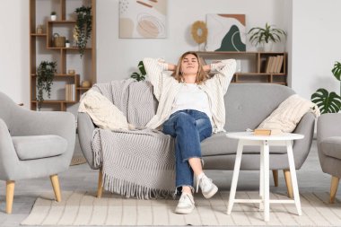 evde bir kanepede oturan genç bir kadın