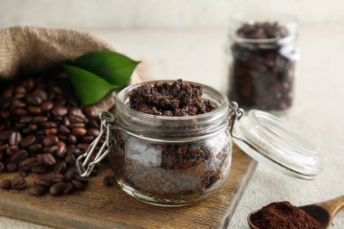 Bir kavanoz kahve, vücut fırçası ve hafif grunge arka planda tahta kesme tahtasıyla kompozisyon, yakın plan.