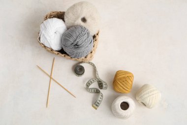 Renkli örgü iplikleri, iğneler ve arka planda şeritlerle dolu bir sepet.