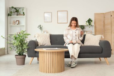 Evdeki koltukta dua boncuklarıyla İncil okuyan genç bir kadın.