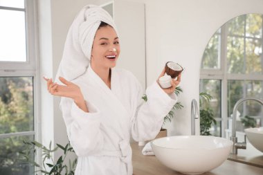 Banyoda aynanın yanında hindistancevizi ve krema dolu güzel genç bir kadın.