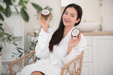 Hindistan cevizli güzel genç bir kadın banyoda sandalyede oturuyor.