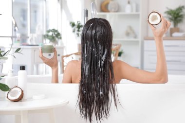 Güzel bir genç kadın, saçında krema kavanozu, hindistan cevizi yağı, küvet, arka manzara...