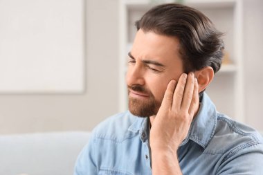 Evde kulak ağrısı çeken genç bir adam, yakın plan.