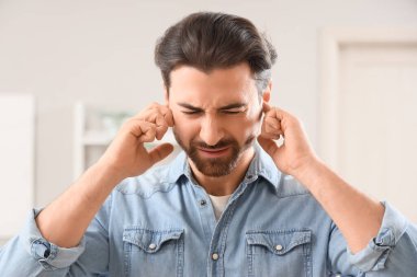 Evde kulak ağrısı çeken genç bir adam, yakın plan.