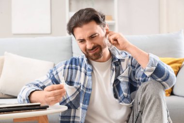 Evde kulak ağrısı çeken genç bir adam.