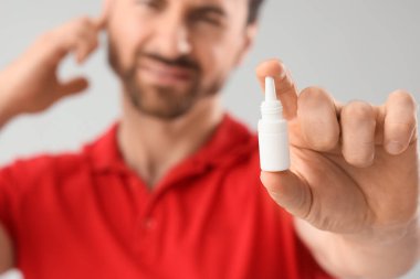 Kulak ağrısı olan genç adam arka planda damla tutuyor, yakın plan.