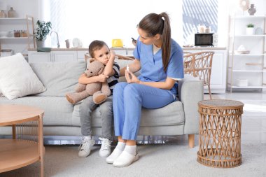 Damlalı bir kadın doktor ve evde kulak ağrısı çeken küçük bir çocuk.