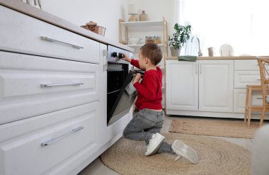 Sevimli küçük çocuk mutfakta fırını yakıyor. Tehlikedeki çocuk