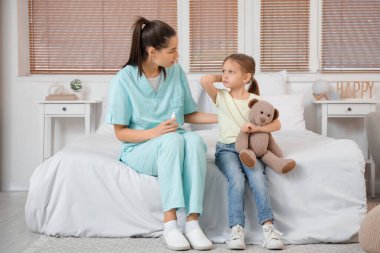 Damlalı bir kadın doktor ve yatak odasında kulak ağrısı çeken küçük bir kız.