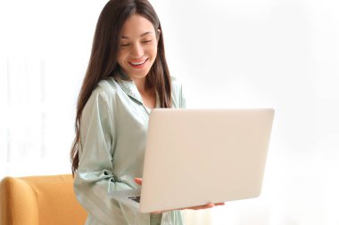 Evde dizüstü bilgisayarla çalışan yeşil pijamalı genç bir kadın.