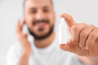 Yatak odasında kulak damlası olan genç adam, yakın plan.