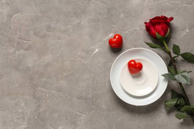 Kırmızı gül ve gri arka planda kalpler olan güzel bir masa. Sevgililer Günü kutlaması