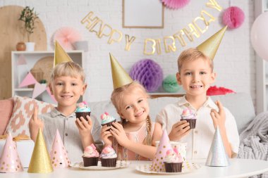 Evde doğum gününü kutlarken elinde kek ve hediye kutuları olan şirin mutlu çocuklar dilek tutuyorlar.